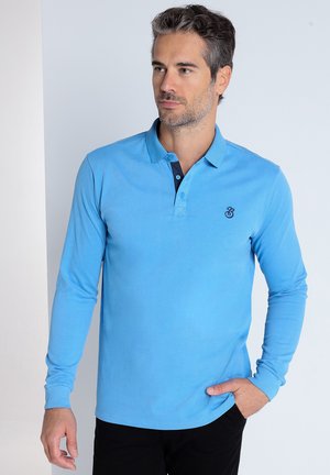 Polo à manches longues bleu en tissu doux, doté d'un col couleur bleu foncé et d'une patte de boutonnage à deux boutons, avec un petit logo sur la poitrine.