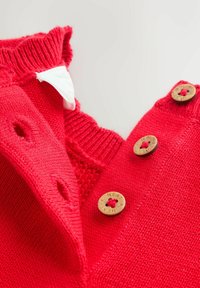 Rode gebreide trui met een geribde kraag, voorzien van drie houten knopen en een gestructureerd gebreid patroon bij de hals.