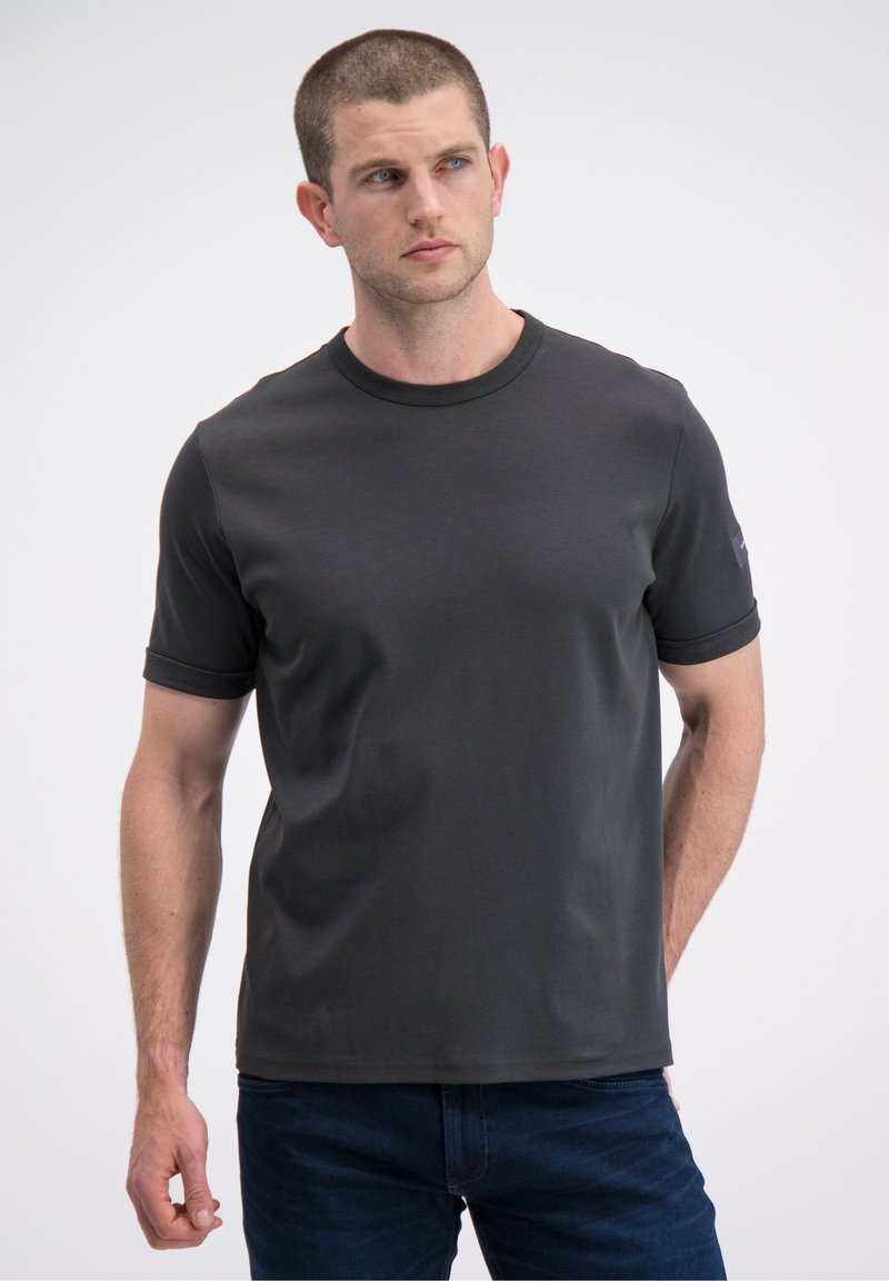 Tamsiai pilka trumpomis rankovėmis marškinėliai iš lygios medžiagos. Turi apvalų kaklo iškirpimą ir apjuostą rankoves. Minimalistinis prekės ženklas kairėje rankovėje.