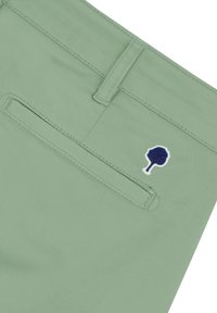 Pantalones verde claro con una textura suave, que cuentan con un bolsillo trasero y un pequeño logo de árbol bordado en navy encima del bolsillo.