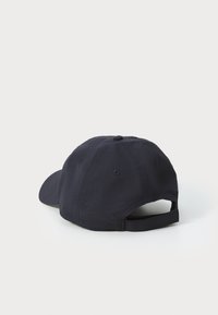 Casquette de baseball bleu marine avec une visière courbée, une sangle arrière ajustable et des trous de ventilation sur les côtés. Fabriquée en tissu texturé.