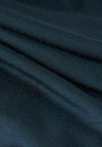 Tmavě modrá bavlněná látka s jemně žebrovanou texturou, složená v vrstvách. Měkký povrch a rovnoměrný povrch bez viditelných vzorů nebo akcentů.