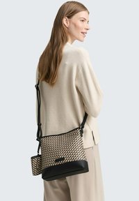 Musterte Woven-Crossbody-Tasche in Beige und Schwarz. Verfügt über ein elegantes Design mit abnehmbarem Mini-Pouch und verstellbarem Trageriemen. Sanfte Textur.