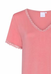 T-shirt rosa chiaro con una texture morbida, caratterizzata da un collo a V e bordo in pizzo floreale su maniche e scollatura. Maniche corte e vestibilità rilassata.