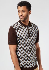 Brown short-sleeve polo with a geometric pattern in light blue and cream. Features a zip-up collar and ribbed cuffs. Soft knit texture.