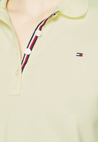 Polo shirt verde chiaro con tessuto texturizzato, caratterizzato da un colletto a righe in contrasto e dettagli con bottoni, oltre a un piccolo logo sul petto.