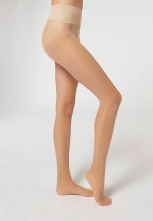 Collants beiges transparents avec une large ceinture lisse et une finition semi-mate, mettant en valeur un teint de peau naturel et une silhouette de jambe.