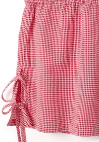Tela de cuadros vichy en rojo y blanco, con una cintura fruncida y lazos a ambos lados, creando un diseño estructurado pero casual.