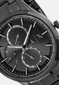 Herrenarmbanduhr mit schwarzem Metallarmband, rundem Gehäuse, dunklem Zifferblatt, silberfarbenen Zeigern und Unterzifferblättern für Minuten und Sekunden. Mit auffälligen Stundenmarkierungen.