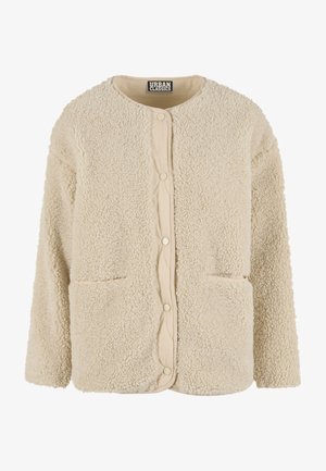 Kremowa bluza polarowa z teksturowanym zewnętrzem, okrągłym dekoltem i dwoma przednimi kieszeniami. Zapięcie na zatrzaski i pikowana podszewka wewnętrzna.