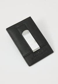 Porte-cartes en cuir noir avec un clip en métal argenté. Surface texturée avec des accents cousus et un branding embossé en bas.