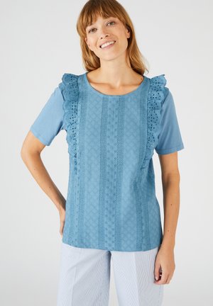 Haut bleu clair à manches courtes avec un détail de volants texturé et des motifs brodés sur le devant. Tissu lisse, encolure ronde, coupe décontractée.