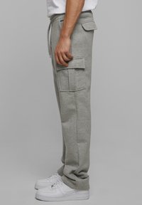 Grijze cargobroek van zachte stof, met zijzakken en een elastische tailleband. Gecombineerd met witte sneakers.