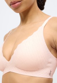 Ροζ σουτιέν bralette με κυματιστό ντεκολτέ, διαθέτει υφασματικό μοτίβο, ρυθμιζόμενους ιμάντες και λεία τελειώματα στην ταινία.