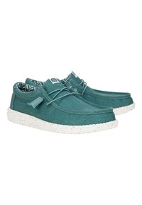 Scarpe di tela color teal con punta tonda e suola in gomma bianca maculata. Presentano lacci regolabili e una foderatura interna a motivo.