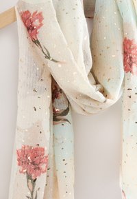 Kerge, läbipaistev sall roosakas lillemustriga, kuldsete detailide ja pastelsel sinisel taustal. Sallil on hajutatud kuldsed laigud.