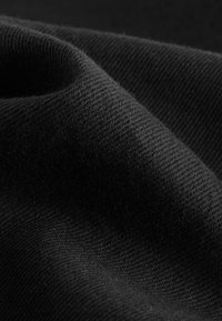 Sort stof med en glat tekstur og en subtil glans, med et diagonalt vævemønster og en blød, fleksibel fald.