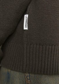 Maglione lavorato a maglia marrone scuro con un motivo testurizzato, orlo a coste e un'etichetta bianca visibile con la dicitura "ORIGINALS™."