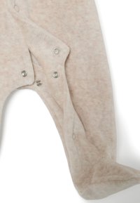 Un body para bebé color crema, hecho de suave forro polar. Presenta cierres a presión a lo largo del frente, con un sutil patrón texturizado en toda su superficie.