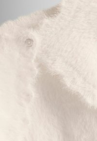 Witte, fluffy stof met een zachte textuur en een subtiele glans. Beschikt over een drukknoopdetail en een afgeronde rand. Geschikt voor comfortabele kleding.