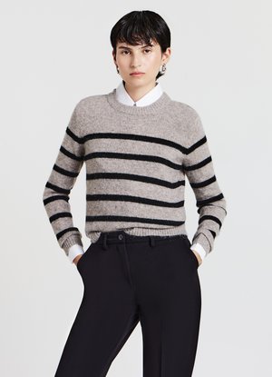 Beige and black striped sweater made of soft material, featuring a round neckline and ribbed cuffs, paired with black trousers.