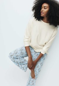 Kremfarvet top med lange ærmer kombineret med lyseblå pyjamasbukser med sort zebra mønster. Blødt stof med afslappet pasform og sænkede skuldre.