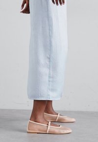 Transparent ballet flats with a soft blush hue and strap detail paired with a light blue textured ankle-length dress.