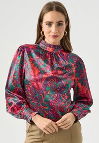 Kolorowa satynowa bluzka z wysoką falbaną przy dekolcie, długimi rękawami oraz żywym wzorem paisley w odcieniach różu, zieleni i pomarańczy.