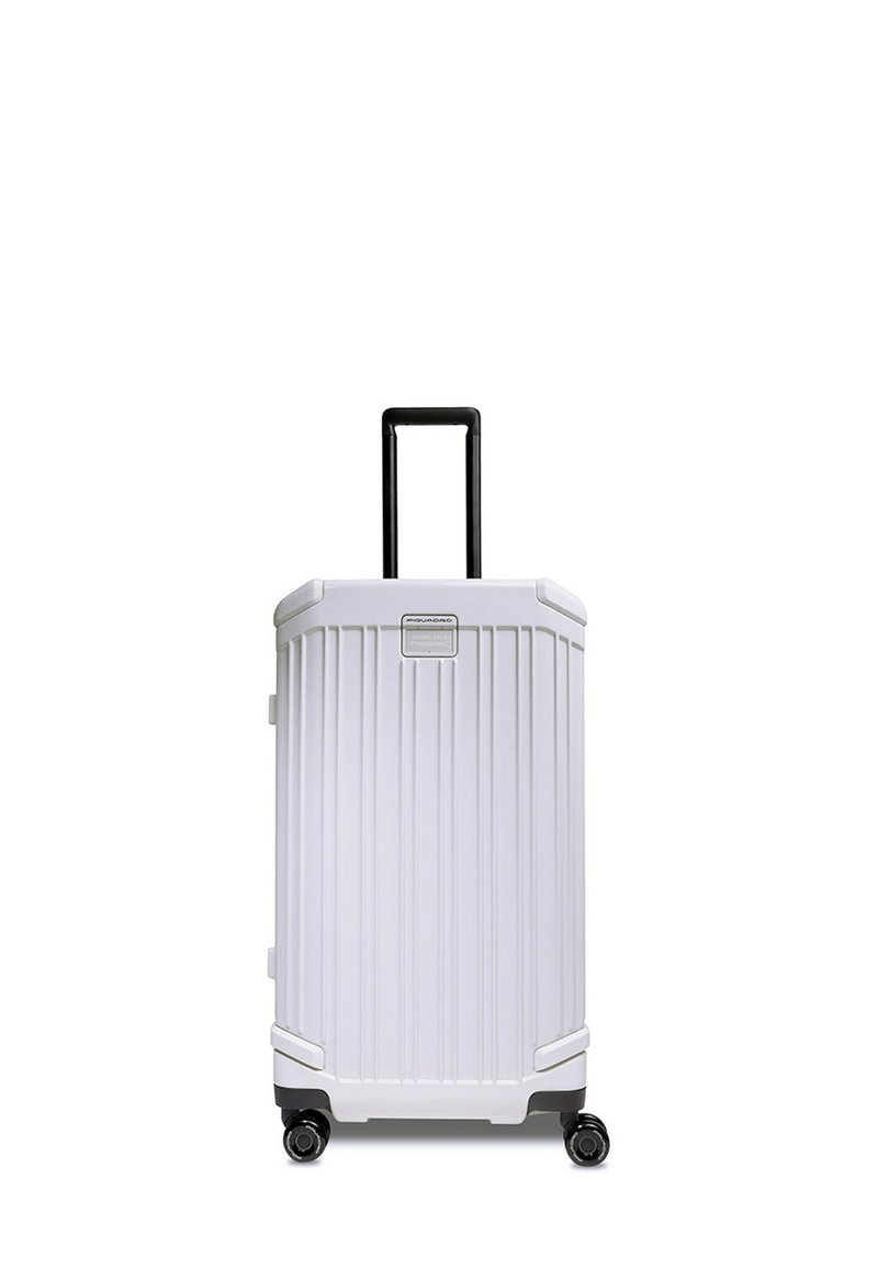 White hardshell suitcase with vertical ribbed design, black telescopic handle, four swivel wheels, and grey accents at the base.