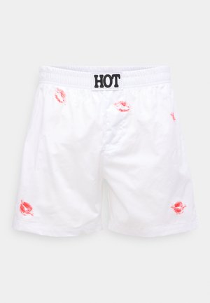 Weiße Shorts mit elastischem Bund, die abgewetzte Bereiche und rote Lippenabdruck-Akzente aufweisen. "HOT"-Label in Schwarz am Bund.