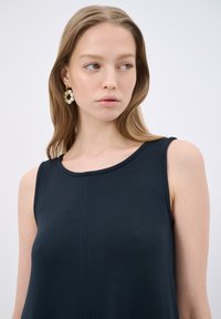 Abito senza maniche di colore blu navy con scollatura rotonda e dettagli di cuciture verticali sottili. Il tessuto ha una consistenza morbida, che completa il design minimalista.