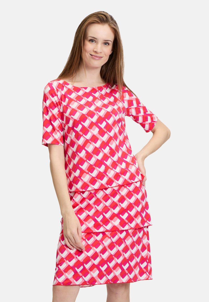 Rosa Kleid mit kurzen Ärmeln, das ein abstraktes Muster aus überlappenden Quadraten in verschiedenen Rosatönen und Weiß zeigt. Weiches, leichtes Material.