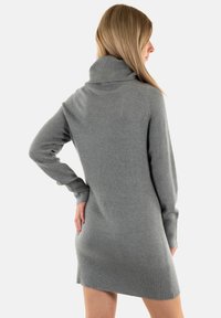 Abito maglione grigio con colletto alto, polsini e orlo a costine. Il tessuto sembra morbido e texturizzato, aderente in vita e morbido nella parte inferiore.