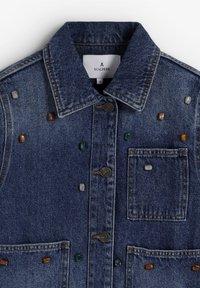 Denimjakke med en mørkeblå vask, klassisk krave, forlommer og flerfarvede dekorative sten påført stoffet.