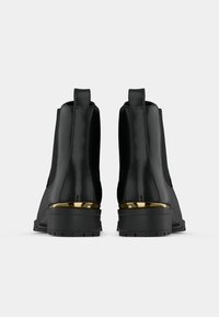 Černé kotníkové boty s hladkým povrchem, zdobené zlatými kovovými doplňky, s širokým podpatkem a elastickými bočními panely.