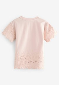 Svetloružové tričko so zvlneným okrajom a vyšívanými detailmi na rukávoch a spodnom leme, s kvetinovými vzormi a výrezmi v tvare očiek.