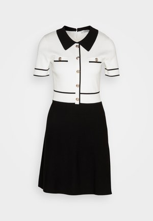 Vestido de manga corta en punto blanco y negro, con cuello de camisa, botones en tono dorado y rayas en contraste en el cuerpo.