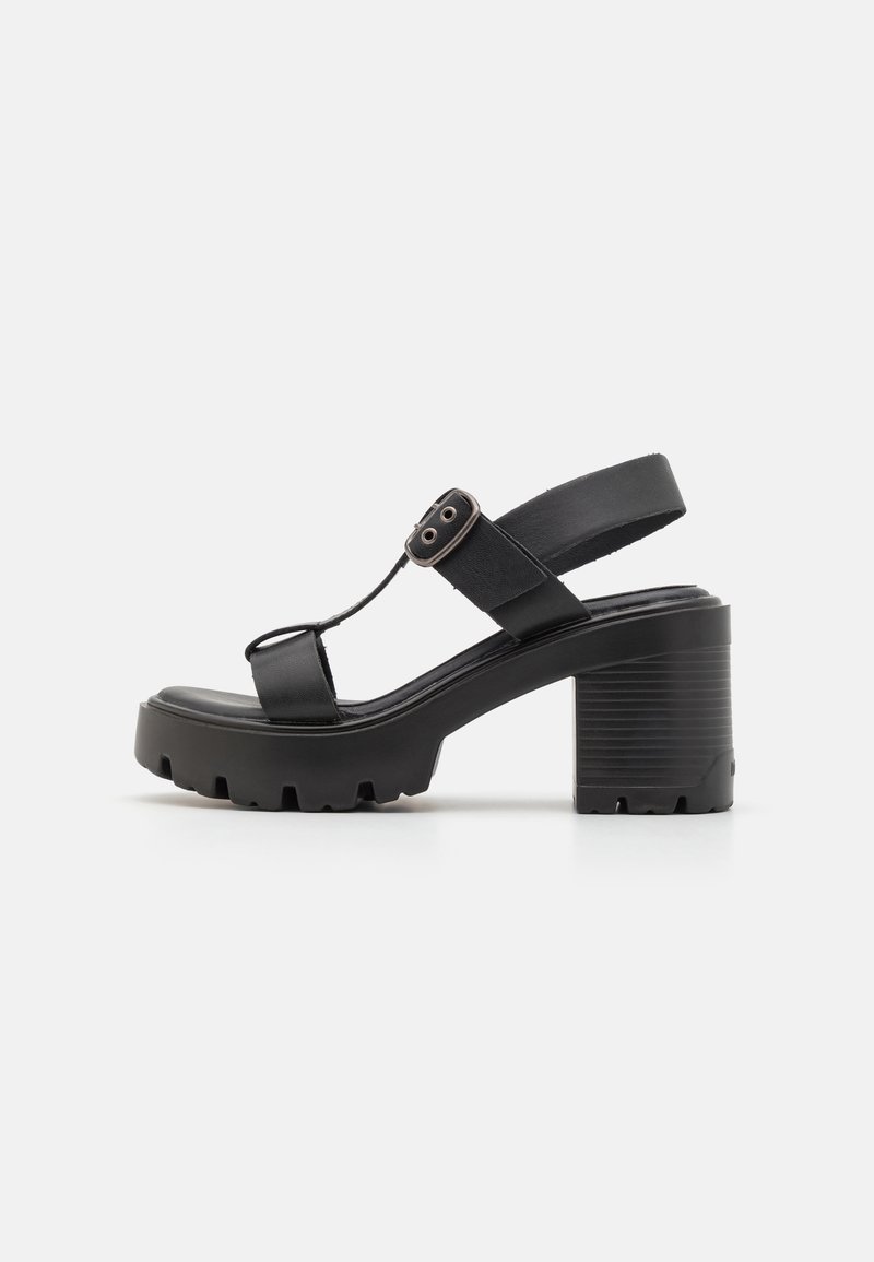 Sandales à plateforme noires avec un talon épais, des sangles larges et une sangle de cheville ajustable avec un détail de boucle. Semelle texturée pour une meilleure adhérence.