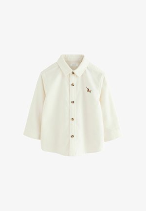 Maglietta per bambini a maniche lunghe color crema con colletto, chiusura frontale con bottoni e piccolo bassotto ricamato in marrone sul petto a sinistra.