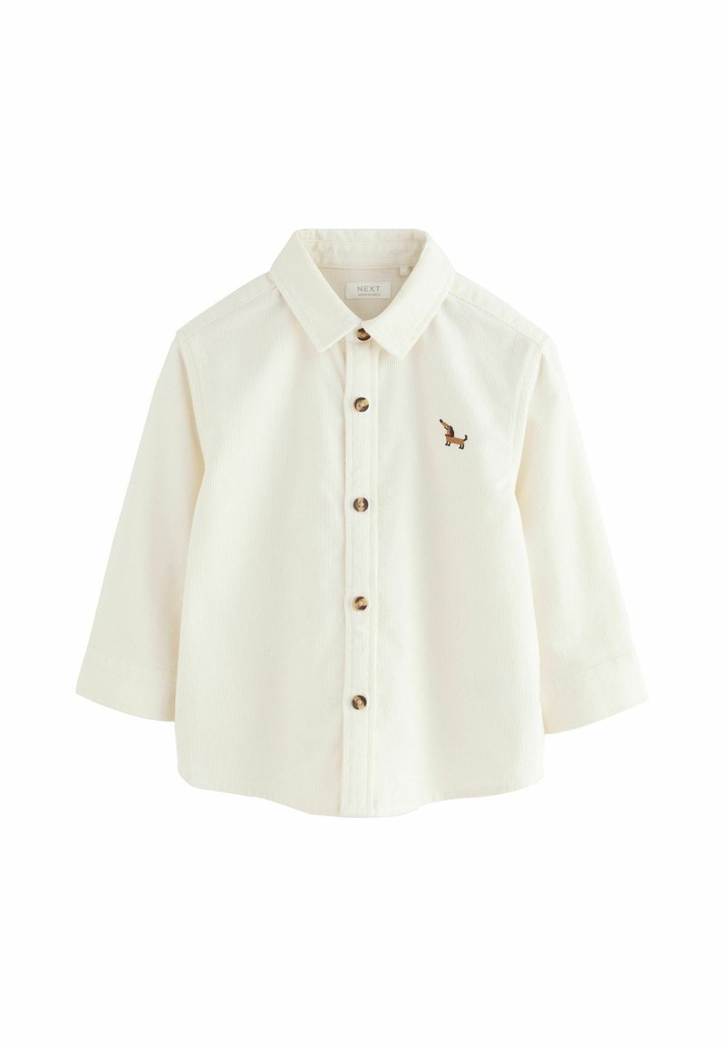 T-shirt crème à manches longues pour tout-petit avec col, devant à boutons et petit teckel brodé marron sur la poitrine gauche.