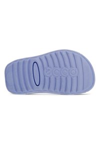 Vaaleanliila kumipohja, jossa on vaakasuorat uurteet ja keskellä logo. Liukas pinta, jossa on hieman kiiltoa ja soikea leikkuujälki.