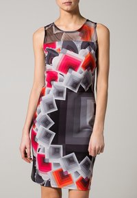 Vaatimattomasti istuva ilman hihoja oleva mekko, jossa on värikäs geometrinen kuvio, sisältäen vaaleanpunaisia, harmaita ja mustia sävyjä. Silkkinen kangas, jossa on läpinäkyvä pääntie.