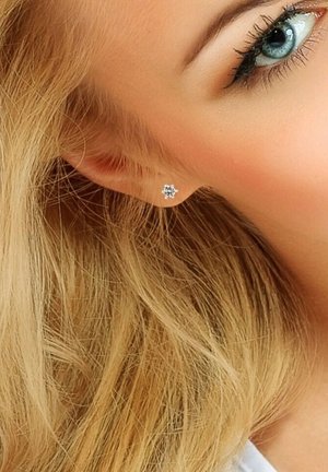 Boucles d'oreilles en argent avec un design floral et des pierres précieuses transparentes, mises en valeur sur des cheveux blonds clairs et montrées sur une oreille.