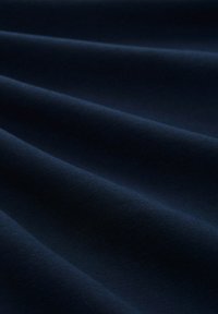 Tela azul marino con una textura suave, que presenta pliegues sutiles y un ligero brillo, destacando su suavidad y la profundidad del color.