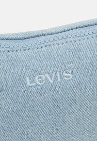 Světle modrá džínovina s odpovídajícím zipem a bílým vyšitým logem Levi's.