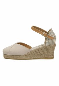 Beige canvas wedge sandaal met enkelbandje, geweven jute middenzool en textuurdetail op de hak. Rond teenontwerp. Verstelbare gesp sluiting.