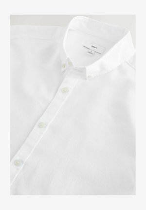 Chemise blanche à boutons en tissu léger. Elle présente un col classique, de petits boutons et une étiquette à l'intérieur du col indiquant "NEXT, L."