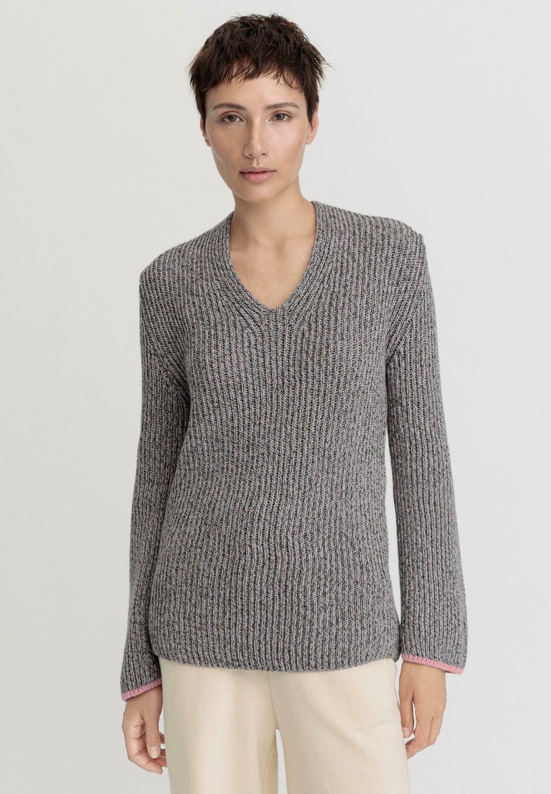 V-Ausschnitt, langärmeliger Pullover mit einem strukturierten grauen Strickmuster. Mit pinken Akzenten an den Bündchen. Slim Fit mit seitlichen Schlitzen am Saum.