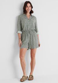 Green and white patterned shirt dress with a collar, short sleeves, elastic waistband, and matching shorts, paired with brown sandals.