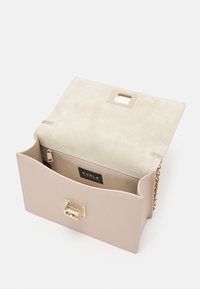 Borsa a tracolla in pelle beige con una chiusura metallica dorata, superficie texturizzata e tracolla in catena; interno con rivestimento in suede chiaro e logo.
